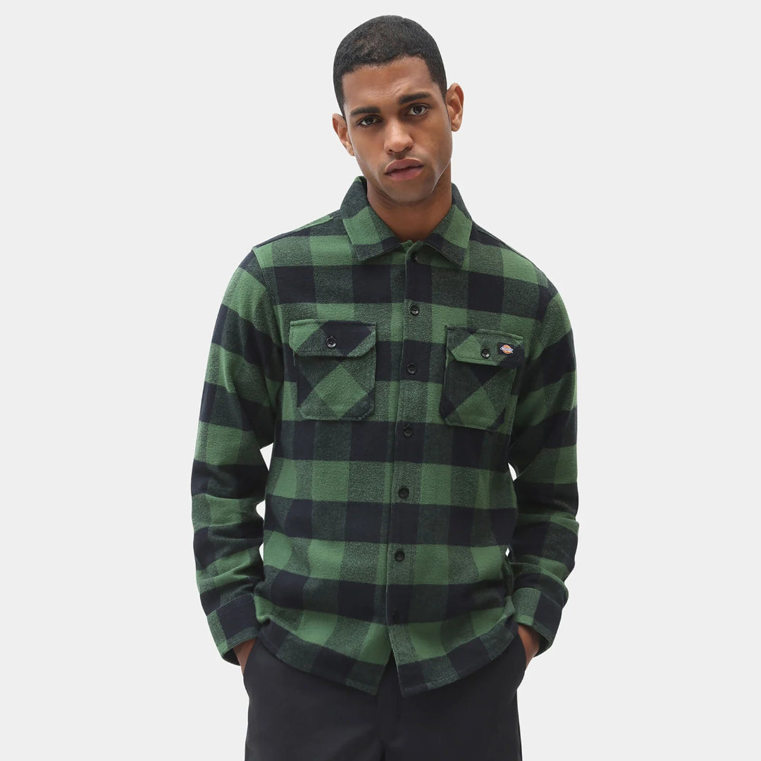 Man wearing a green and black plaid shirt on a white background