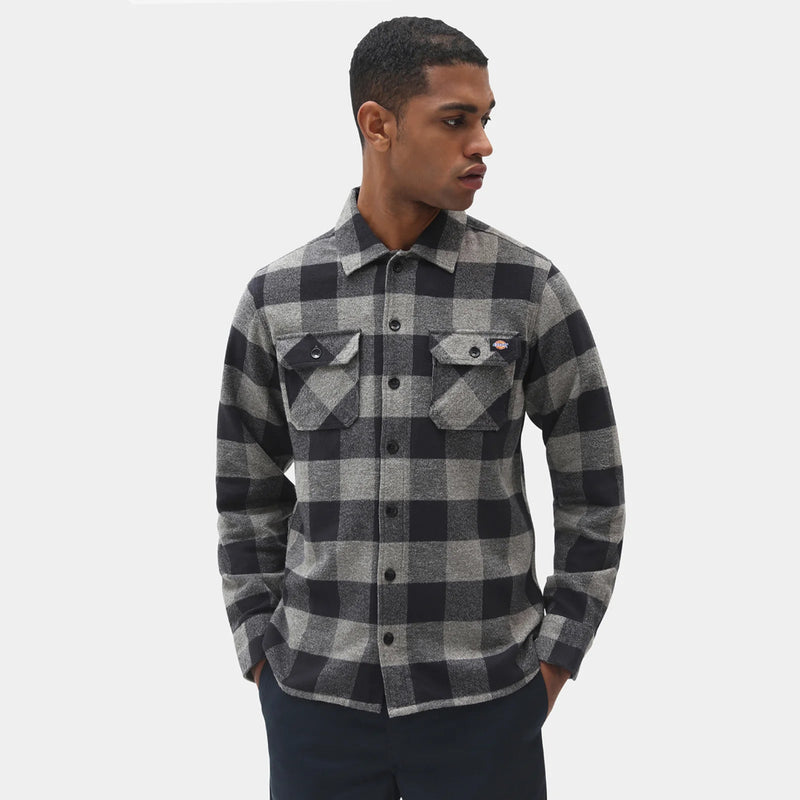 Man wearing a black and gray checkered long sleeve flannel shirt on a white background