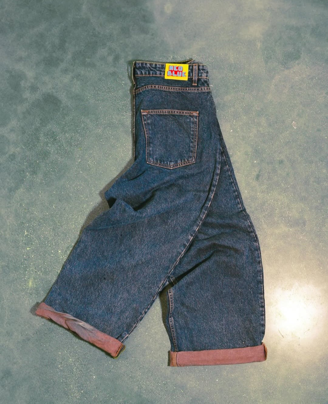 Pair of blue jeans with a visible brand label on a textured surface